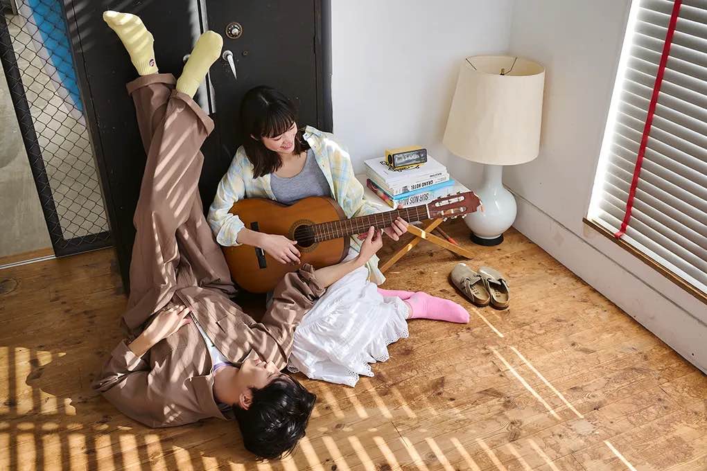 ギターを弾く女性と寝転んで微笑む男性